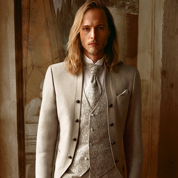 Ein Mann im Anzug mit Krawatte steht selbstbewusst in einem hell erleuchteten Raum und strahlt Professionalität und Souveränität aus.