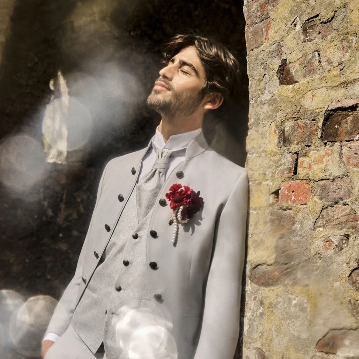 Ein Mann im Anzug mit Krawatte lehnt lässig an einer Wand und strahlt Selbstbewusstsein und Professionalität aus.