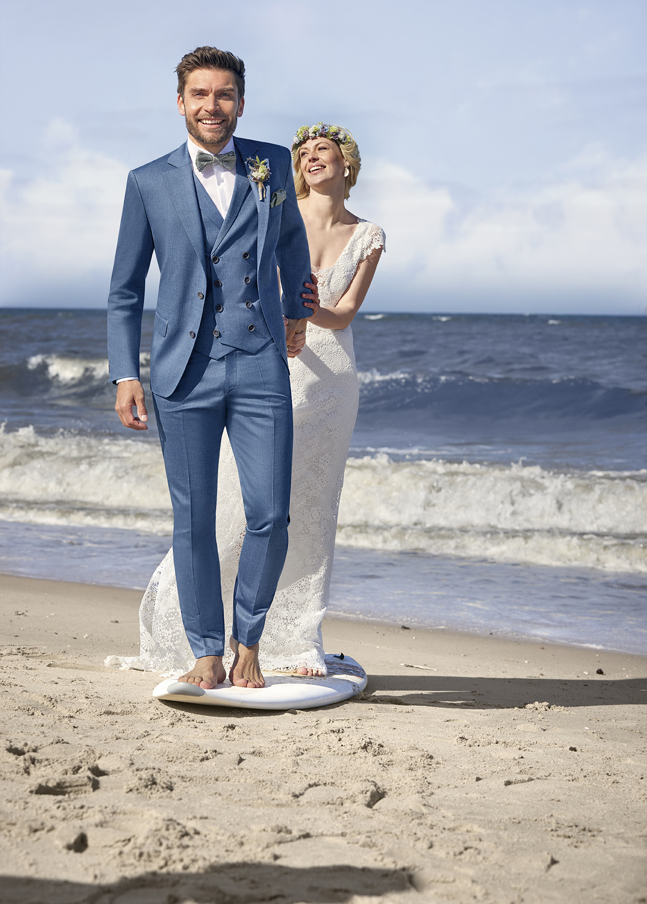 Ein Mann und eine Frau spazieren am Strand entlang, im Hintergrund plätschern sanft die Wellen ans Ufer.