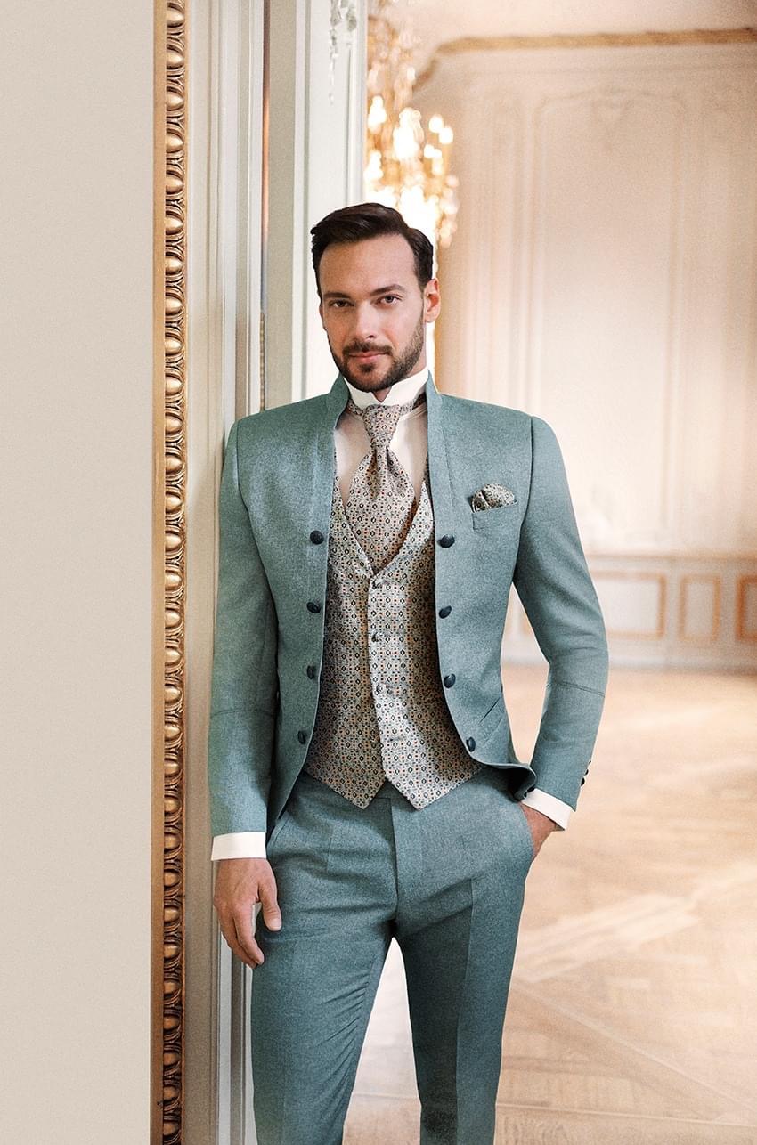 Ein Mann in einem blauen Anzug und einem weißen Hemd steht selbstbewusst da und vermittelt ein professionelles Erscheinungsbild.