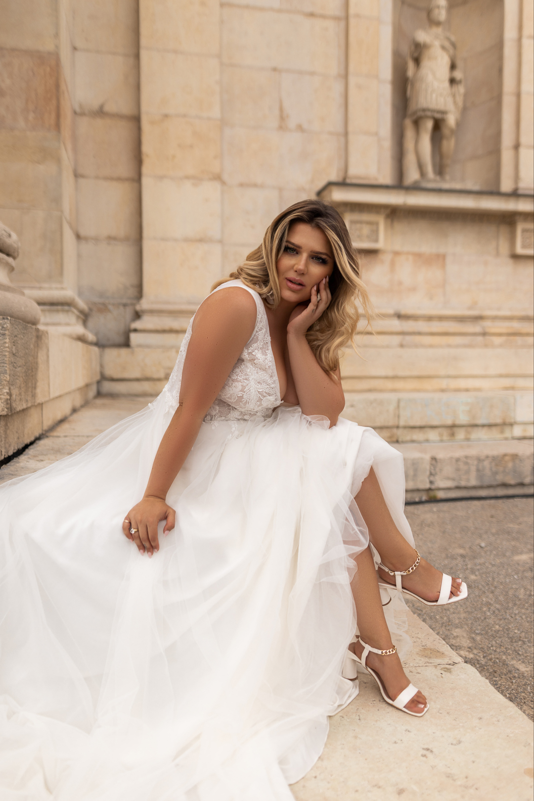 Eine Frau im Brautkleid sitzt anmutig auf den Stufen und strahlt an ihrem besonderen Tag Freude und Eleganz aus.